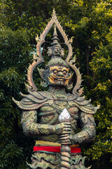 Fierce, ornate Yaksha guardian statue with gold and Thai motifs. It protects sacred temple spaces, often seen at Mahadevalai, Bangkok.