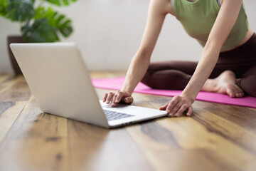 Naklejka premium Laptop-Focused Shot of Middle-Aged Asian Woman Taking Online Yoga Class at Home