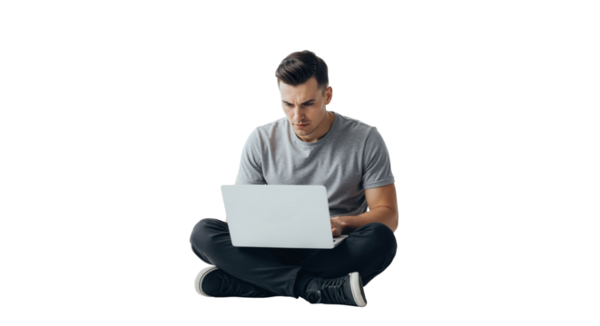 Man working on laptop in cross-legged position with focused expression