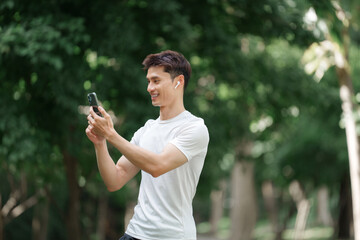 Young man using smartphone and wireless earbud