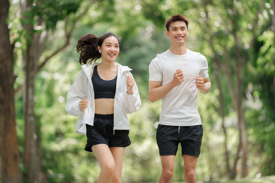Happy young asian couple jogging in park together