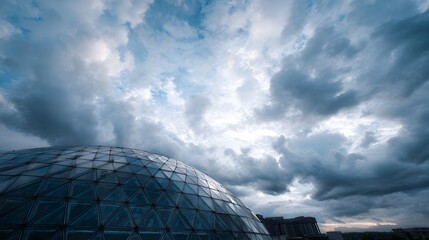 A modern glass geodesic dome structure stands against a dramatic cloudy sky conveying innovation and architectural design