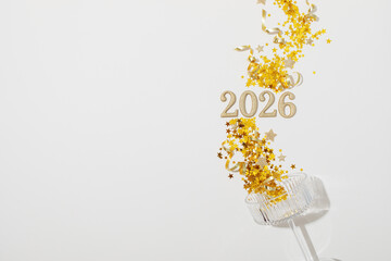2026 Happy New Year glittering golden numbers in champagne glass with festive party decoration on...