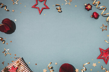 Gift box, red paper Christmas decoration and metal gold stars on blue background, flat lay. Natural...
