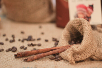 Aromatic coffee bean and cinnamon spice in rustic burlap sack create warm scene. Brown ingredient on table with soft focus background, feeling cozy and natural