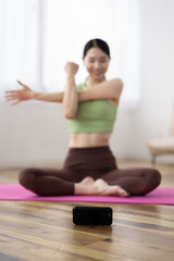 Smartphone-Focused Shot of Japanese Woman Taking Online Yoga Class at Home