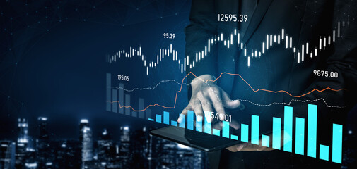 A businessman uses a tablet displaying financial graphs against a futuristic city backdrop,...