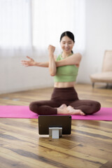 Tablet-Focused Shot of Middle-Aged Japanese Woman Taking Online Yoga Class at Home