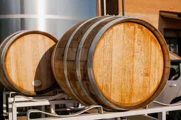 Barrel oak wine barrels outside winery production area in sunlight, close-up of wood barrels for aging wine in modern winery facility