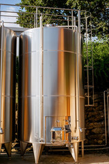Modern stainless steel wine fermentation tank in an outdoor winery setup under natural daylight