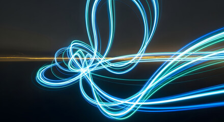Abstract streaks of bright neon blue and green light trails move dynamically in the dark