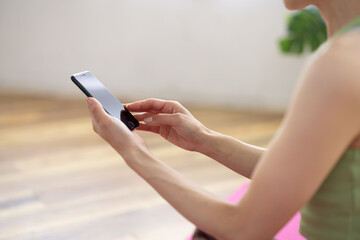 Close-Up of Smartphone in Hands on Yoga Mat at Home