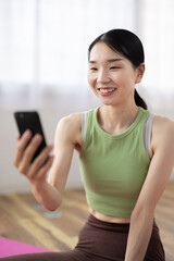 Smiling Woman in Activewear Using Smartphone at Home