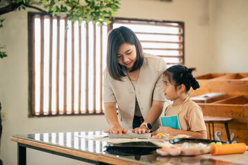 A Young Mother and Her Daughter Enjoying Quality Time Together While Baking in a Bright and Airy...