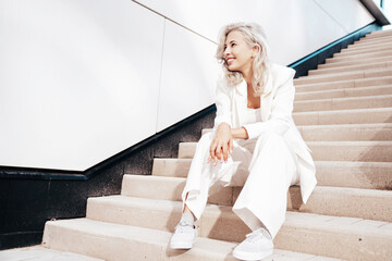 Young beautiful blond woman wearing nice trendy white suit jacket. Smiling model posing in the...