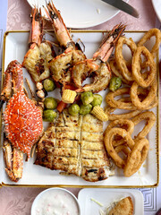 Grilled seafood platter with prawns, crab, fish fillet, fried calamari rings, vegetables. Seafood menu. Top view.