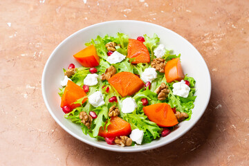 Salad with persimmon, feta cheese, pomegranate and nuts. Healthy eating. Vegetarian.