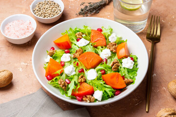 Salad with persimmon, feta cheese, pomegranate and nuts. Healthy eating. Vegetarian.