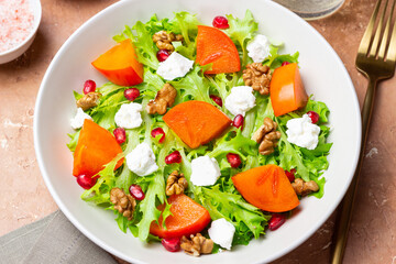 Salad with persimmon, feta cheese, pomegranate and nuts. Healthy eating. Vegetarian.