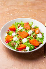 Salad with persimmon, feta cheese, pomegranate and nuts. Healthy eating. Vegetarian.