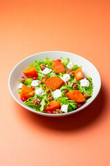 Salad with persimmon, feta cheese, pomegranate and nuts. Healthy eating. Vegetarian.