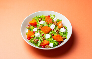 Salad with persimmon, feta cheese, pomegranate and nuts. Healthy eating. Vegetarian.