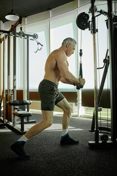 Senior Man Exercising on Cable Machine in Modern Gym Setting