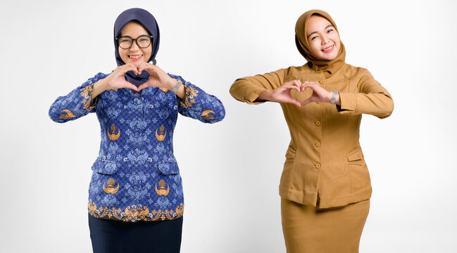 Indonesian civil servant women wearing brown uniform and batik Korpri make heart hand gesture while smiling. Concept of teacher, ASN, PNS, and government appreciation.
