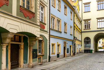 Obraz premium Colorful townhouses along narrow cobbled street in Wroclaw Old Town, restored facades, historic urban architecture, archway passage, quiet pedestrian area without traffic