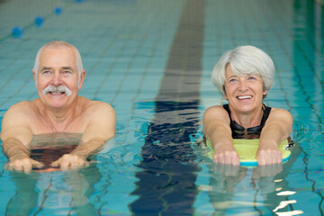 senior couple exercising with floats in swimming pool