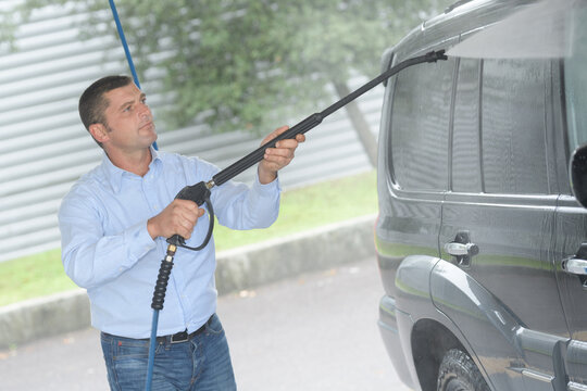 man pressure washing vehicle
