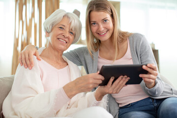 cheerful girl with an elderly woman using a digital tablet