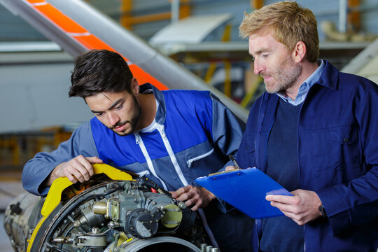 supervisor observing trainee engineer in airport hangar
