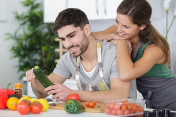 girl leaning on boyfriend as he prepares vegetables for meal
