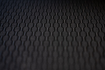 Abstract background of a dark, textured surface with a repeating geometric pattern. Macro shot with...