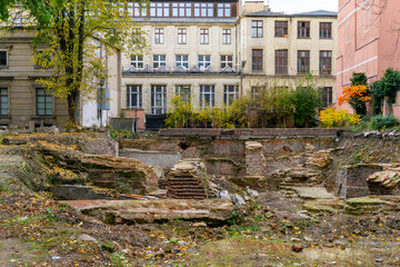 Exposed brick foundations and walls at an archaeological excavation site in city center, autumn surroundings, open area between urban residential buildings