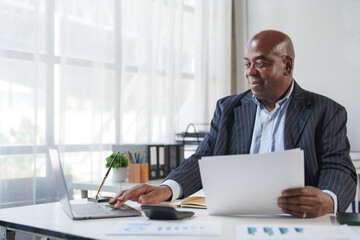 African american businessman working with laptop and papers
