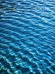 Obraz premium Abstract Blue Water Texture: Sunlight Reflections & Ripples - Calming Ocean Wave Background for Summer Concepts