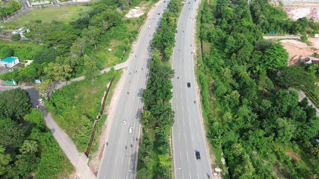 Verdant aerial vista: A busy tropical highway gracefully carves through lush green landscapes