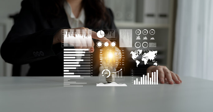 A businesswoman engages with innovative technology in a modern workspace, utilizing virtual interfaces to analyze data and generate creative ideas symbolized by a glowing light bulb. Impute