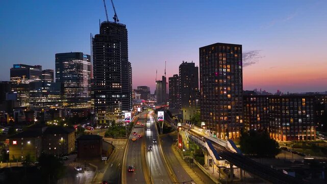 Night aerial views of London&rsquo;s skyline, showcasing illuminated towers, highways, trains, and vibrant urban lights during twilight. Cinematic city atmosphere.