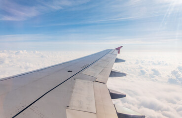 Obraz premium View from the airplane window at a beautiful cloudy sky and the airplane wing