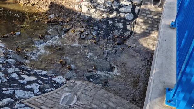 freeway bridge drainage. A sound-absorbing wall with holes lets water through. gutters collect water from gutter of water line. pipe with flexi rubber connection. slowing down flow of water roughening