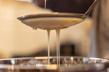 Medicinal honey from the Amazonian stingless bee Melipona eburnia, cultivated by native Amazonians of Peru, during the process of filtering and packaging the honey in glass containers