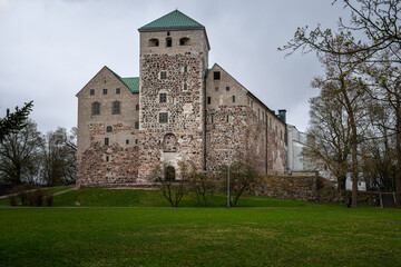 Turku Castle stands surrounded by green grass and trees.