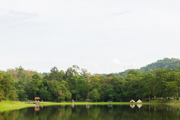 Large, well-maintained green lawn and open space bordered by dense tropical forest trees at Namtok Sam Lan National Park, Saraburi, Thailand.