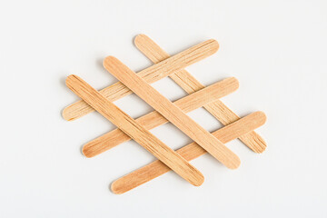 A pattern created by several natural wooden craft sticks or popsicle sticks, arranged in an overlapping, grid-like design on a clean white background.