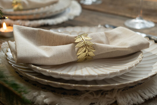 Elegant table setting. Festive table with white plates decorated napkin and golden ring.
