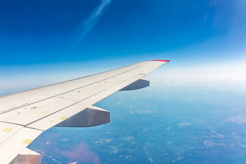 Fototapeta premium View from the airplane window at a beautiful blue clear sky and the airplane wing