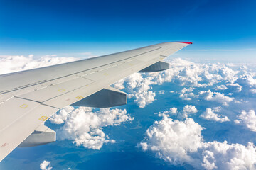 View from the airplane window at a beautiful cloudy sky and the airplane wing